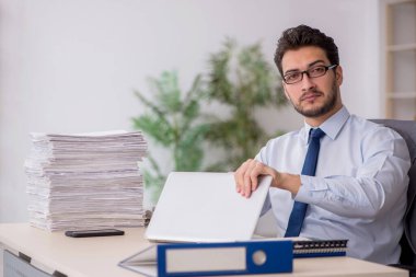 Young employee and too much work at workplace