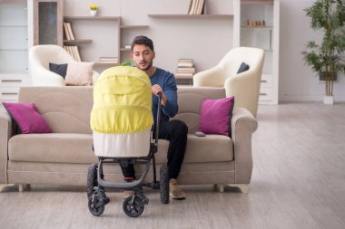 Evde yeni doğan çocuğa bakan adam.