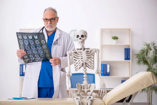 病院で骨格を調べる老医師 — ストック写真