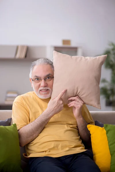 Aged man with many pillows at home