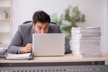 Young employee and too much work at workplace