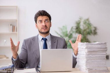 Young employee and too much work at workplace