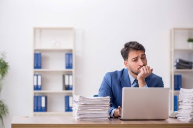 Young employee and too much work at workplace
