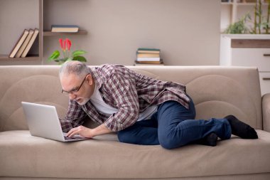 Yaşlı adam evde çalışıyor.