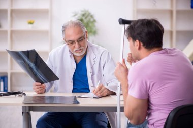 Genç bacak yaralı hasta yaşlı doktor radyolojisti ziyaret ediyor.