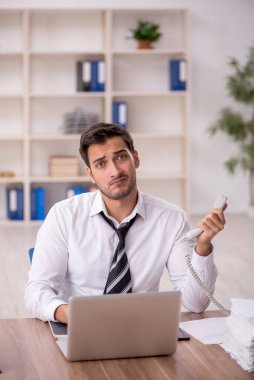 Genç işadamı işyerinde oturuyor.