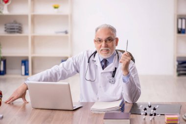 Klinikte çalışan yaşlı bir doktor.
