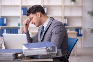 Young employee and too much work at workplace