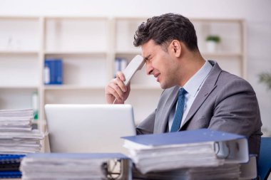 Young employee and too much work at workplace