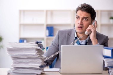 Young employee and too much work at workplace