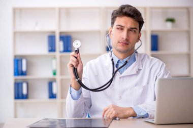 Klinikte steteskop tutan genç bir doktor.