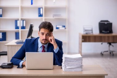 Genç bir erkek çalışan ve ofiste çok fazla iş var.