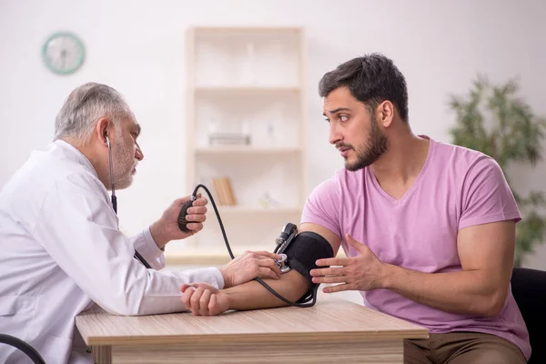 老医生测量年轻病人的血压 — 图库照片
