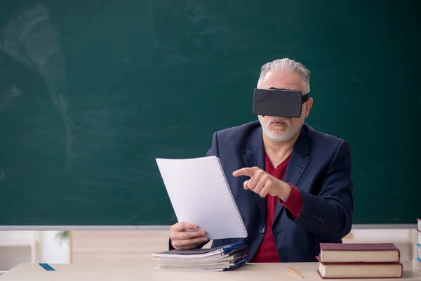 Old teacher wearing virtual glasses in the classroom