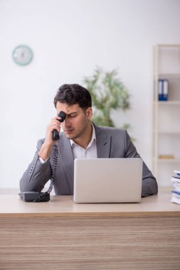 Young employee and too much work at workplace