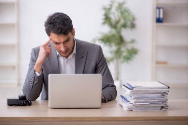 Young employee and too much work at workplace
