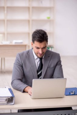 Genç işadamı işyerinde oturuyor.