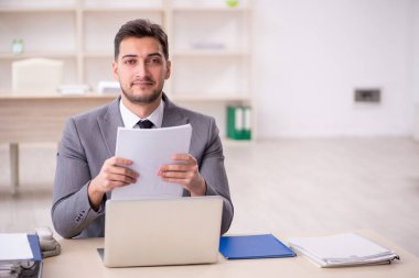 Genç işadamı işyerinde oturuyor.