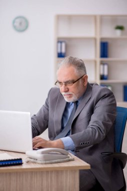 Old employee sitting at workplace