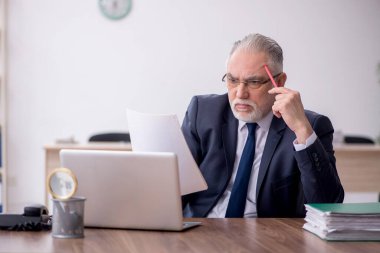 Old employee sitting at workplace