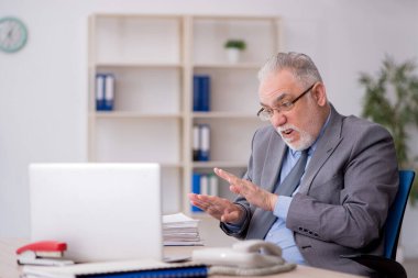 Old employee sitting at workplace