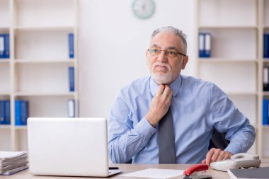 Old employee sitting at workplace