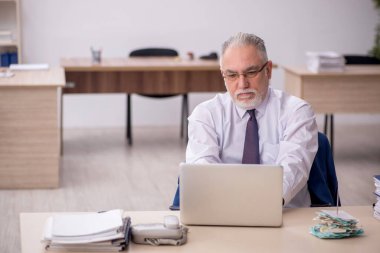 Old employee sitting at workplace