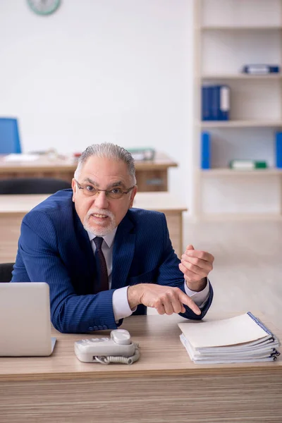 stock image Old employee sitting at workplace