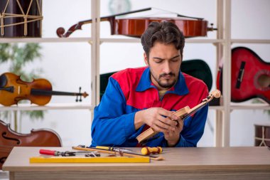 İçeride müzik aletlerini tamir eden genç bir adam.