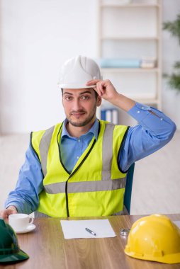 Genç mimar işyerinde oturuyor.