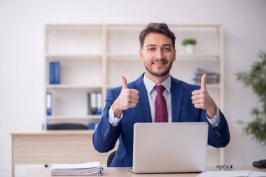 Genç işadamı işyerinde oturuyor.