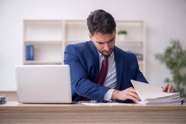 Genç işadamı işyerinde oturuyor.