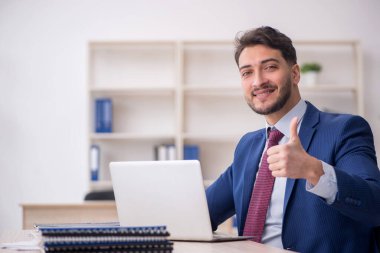 Genç işadamı işyerinde oturuyor.