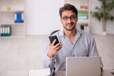 Genç öğrenci ofiste telefonla konuşuyor.