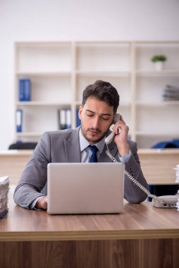 Young employee and too much work at workplace