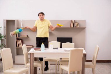 Genç adam evi temizliyor.
