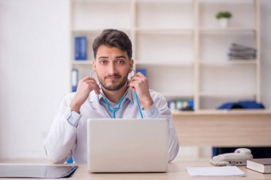 Hastanede steteskop tutan genç bir doktor.