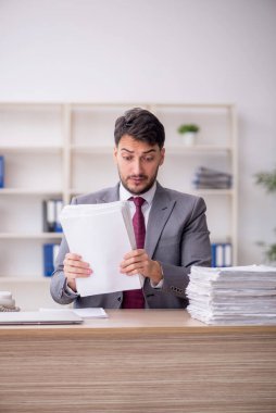 Young employee and too much work at workplace