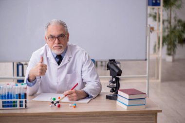 Old chemist teacher sitting in the classroom