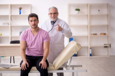 Genç hasta yaşlı doktoru ziyaret ediyor.