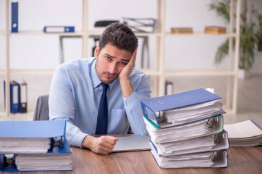 Young employee and too much work at workplace