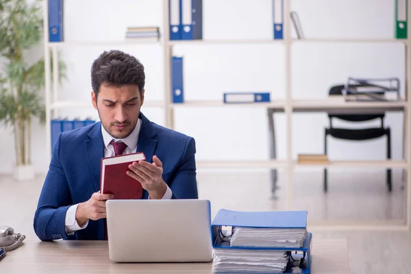 Stock image Young businessman employee reading book in the office