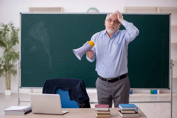 Old teacher holding megaphone in the classroom