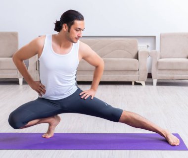 Genç adam evde antrenman ve egzersiz yapıyor.