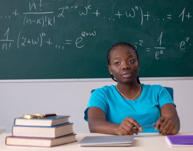 Kara tahtanın önündeki siyah kız öğrenci.