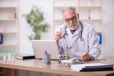 Klinikte çalışan yaşlı bir doktor.