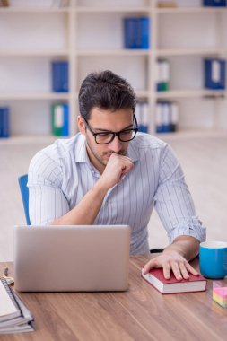 Young businessman employee reading book at workplace