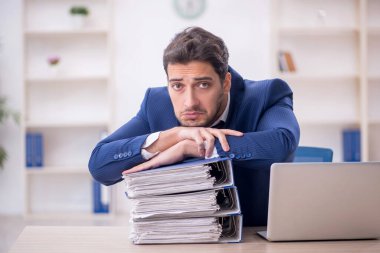 Genç işadamı ve işyerinde çok fazla iş var.