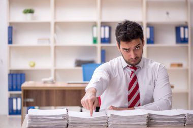 Genç işadamı ve işyerinde çok fazla iş var.