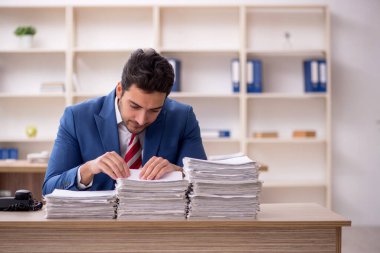 Genç işadamı ve işyerinde çok fazla iş var.